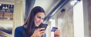 девушка держит телефон и банковскую карту в руках
